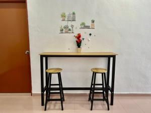 una mesa con dos taburetes y un jarrón con flores en Cozy255#4pax#Wifi#NearAeonAlma#5kmtoIconCity, en Bukit Mertajam