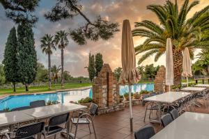 a restaurant with tables and umbrellas next to a swimming pool at Camping Vilanova Park in Vilanova i la Geltrú