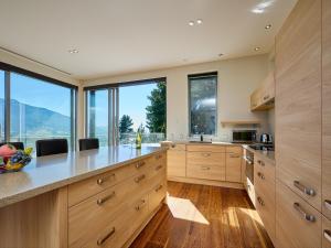 a large kitchen with wooden cabinets and large windows at Ata Rangi Lodge - Kaikoura Holiday Home in Kaikoura