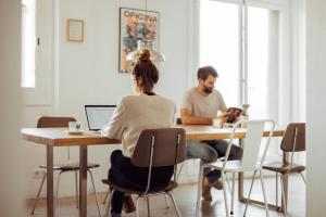 un homme et une femme assis à une table avec un ordinateur portable dans l'établissement Casa Jam Barcelona, à Barcelone