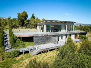 a house on a hill with a wooden deck at Ata Rangi Lodge - Kaikoura Holiday Home in Kaikoura