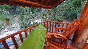a green hammock on a porch with two chairs at Floor river view in Cat Tien