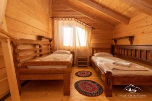 ボロフタにあるGirska Hatyna Vorohtaのログキャビン内のベッドルーム1室(ベッド2台付)