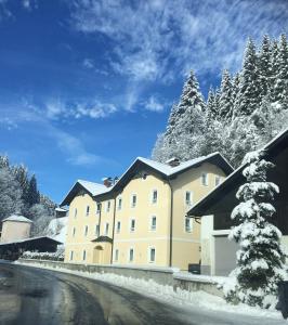 a large yellow building with snow on the ground at Appartements Feroli in Dienten am Hochkönig