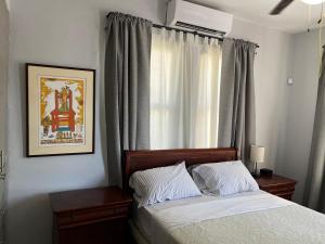 1 dormitorio con 1 cama y una ventana con cortinas en La Estancia Vacation Rentals, en San Juan
