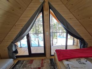 1 dormitorio con ventanas grandes en una cabaña de madera en HIŠA ZIMAZAKON BLOKE, en Nova Vas