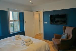 a bedroom with blue walls and a bed with towels on it at Irish Sea Cottage in Annalong
