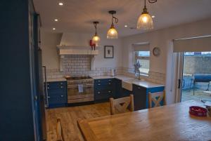 eine Küche mit blauen Schränken und einem Holztisch in der Unterkunft Irish Sea Cottage in Annalong
