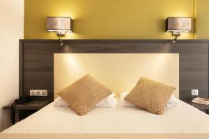 a bedroom with a bed with two lamps on it at Hôtel Le Collier in Antibes