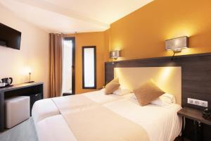 una habitación de hotel con una gran cama blanca con paredes amarillas en Hôtel Le Collier, en Antibes