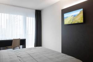 a hotel room with a bed and a television on the wall at Hotel Bahnhof Zollikofen in Zollikofen