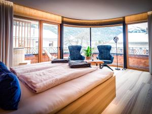 ein großes Bett in einem Zimmer mit einem großen Fenster in der Unterkunft HAUSEREI am Lech in Steeg