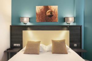 1 dormitorio con 1 cama con 2 lámparas en la pared en Hôtel Le Collier en Antibes