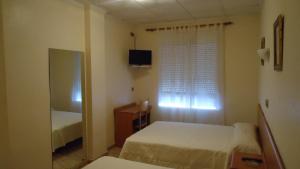 - une petite chambre avec 2 lits et une fenêtre dans l'établissement Pension Los Cisnes, à Puerto de Mazarrón