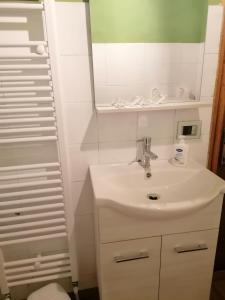 a white bathroom with a sink and a mirror at CasaGiulia in Sillano