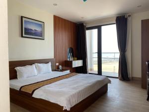 sypialnia z dużym łóżkiem i dużym oknem w obiekcie Hottel HÙNG PHƯƠNG cô tô w mieście Đảo Cô Tô