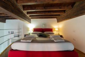 a bedroom with a large bed with red pillows at Guelfi loft in a historic palace in Florence