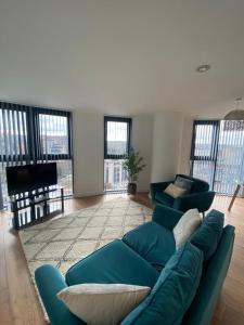 una sala de estar con un sofá azul en una habitación con ventanas en Blonk Street I Quarter Apartment en Sheffield