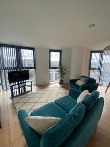 a large blue couch in a living room with windows at Blonk Street I Quarter Apartment in Sheffield