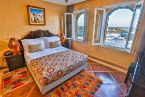 a bedroom with a bed and two windows at Riad Mimouna in Essaouira