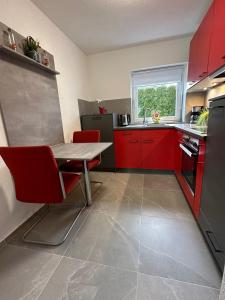 uma cozinha com armários vermelhos, uma mesa e cadeiras vermelhas em Zum Sternberg em Münsingen