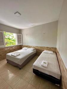 two beds in a large room with a window at Pousada Durma Bem in Tianguá