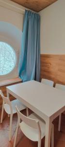 una mesa y sillas blancas en una habitación con ventana en La casetta di Diego, en Abetone