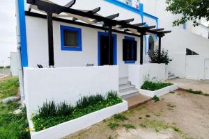 a white and blue house with a fence at Cosy Messaria in Mesaria