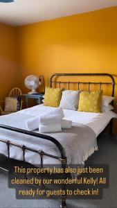 a bedroom with a bed with a yellow wall at Goodwins' by Spires Accommodation a comfortable place to stay close to Burton-upon-Trent in Swadlincote