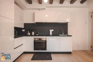 uma cozinha com armários brancos e um forno preto em Michael&Renate - Stylish studio em Trieste