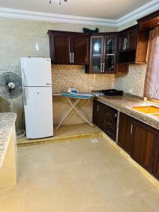 a kitchen with a white refrigerator and wooden cabinets at شقق الياسمين in Jerash
