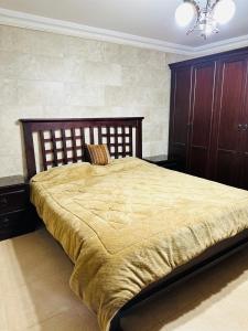 una camera con un grande letto con testiera in legno di شقق الياسمين a Jerash
