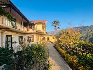 a house with a pathway in front of a mountain at The Tranquil Farm Stay in Thode