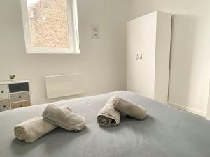 2 handdoeken op een bed in een witte kamer bij * Le Droma D’or * Appartement Confort * Centre-ville in Calais