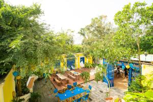 uma vista superior de um restaurante com mesas azuis e árvores em The Cuckoo's Nest Hostel and Bar managed by Hoianese em Hoi An