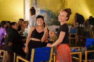 dos mujeres de pie junto a otras sosteniendo copas de vino en The Cuckoo's Nest Hostel and Bar managed by Hoianese en Hoi An