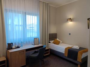 ルブニエビツェにあるLeśne Nieboのベッド、デスク、ノートパソコンが備わるホテルルームです。