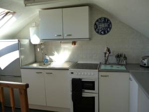a kitchen with white cabinets and a stove and a sink at Poppy's Place Annex in Camelford North Cornwall in Camelford