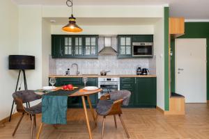 eine Küche mit grünen Schränken sowie einem Tisch und Stühlen in der Unterkunft Grano Green Comfort Residence by Renters Prestige in Danzig