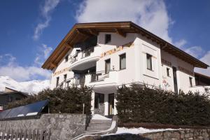 a white building with snow on the mountains at Apart Alpen Royal in Nauders