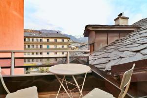 a white table and chairs on a balcony with buildings at Duplex de charme au cœur de la vieille ville de Sion in Sion