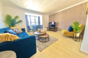 a living room with a blue couch and a tv at Modern 4-Level Townhouse for 8 Free Parking Bournemouth in Bournemouth