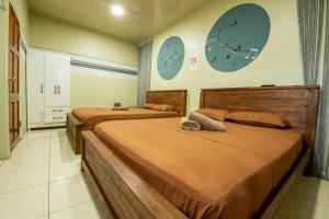 two beds in a room with clocks on the wall at Rumanija's Airport Rooms in Zanderij