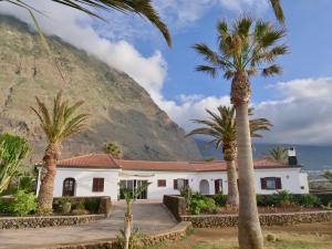 une maison avec des palmiers en face d'une montagne dans l'établissement Finca Afortunada, à Las Puntas