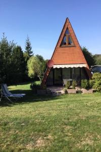 una pequeña casa con techo rojo en un campo en Gemütliches Ferienhaus mit sonniger Terrasse Frankenwald nähe Badesee Smart-TV, en Lichtenberg