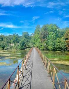 un ponte su un fiume con alberi sullo sfondo di Jolie maison 2 chambres - CLIM MOBILE - TV - Proche d un lac a Ruelle-sur-Touvre