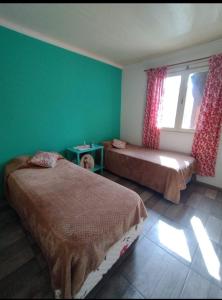 2 camas en una habitación con paredes verdes y ventana en Rocio en Ushuaia