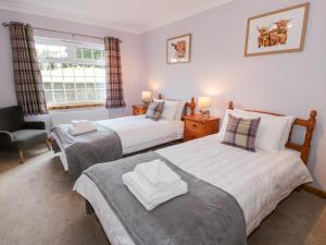 a bedroom with two beds and a chair and a window at Whiteside Cottage in Darvel