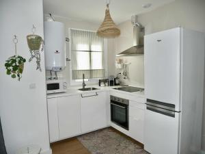 a kitchen with white cabinets and a white refrigerator at Casa Carivid en el centro y con parking gratis in Sanlúcar de Barrameda