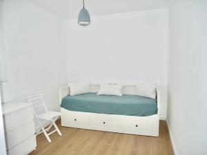 a white bedroom with a white bed and a chair at Casa Carivid en el centro y con parking gratis in Sanlúcar de Barrameda